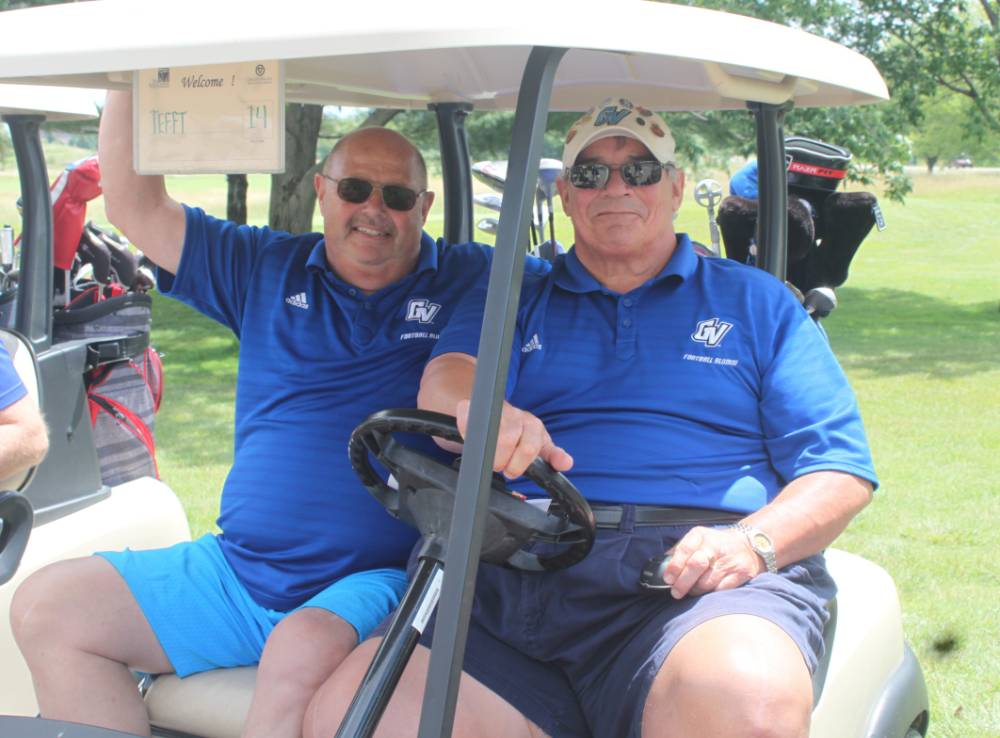 2 men in blue in golf cart